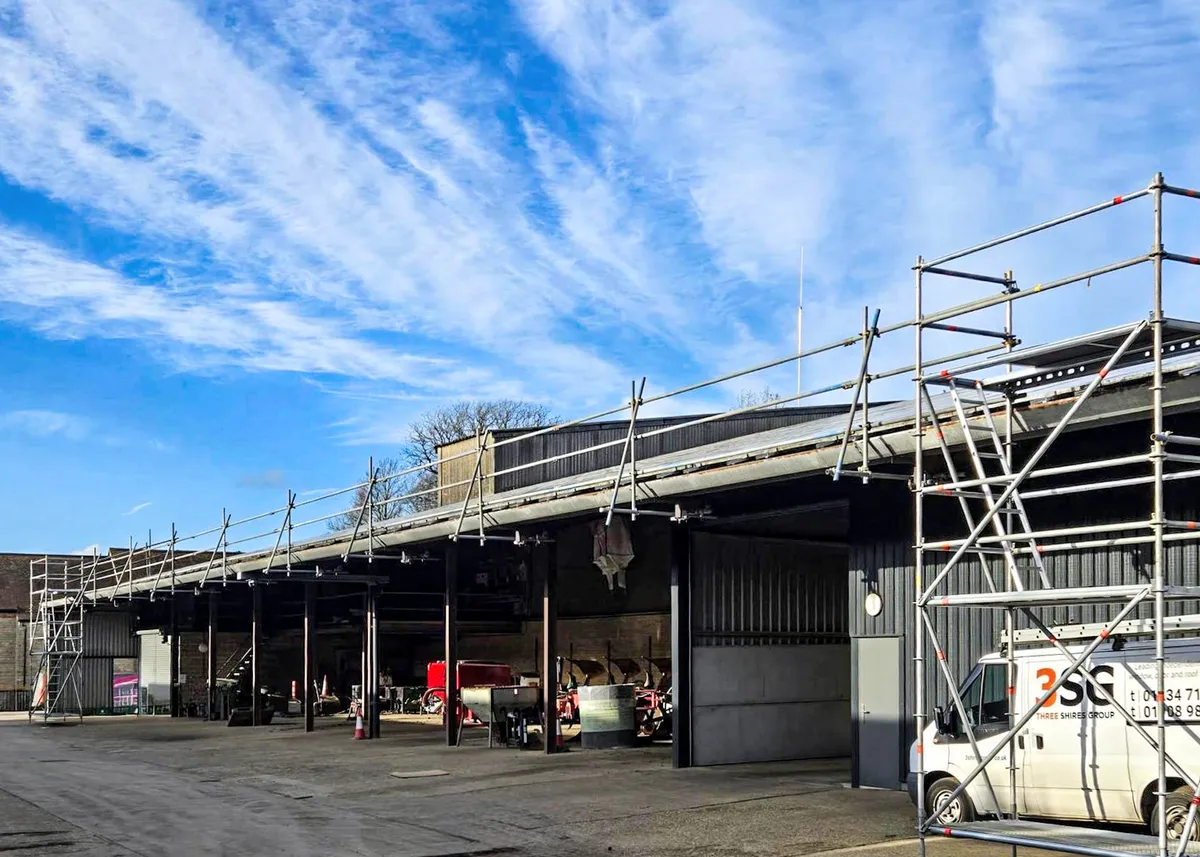 Scaffold tower and edge protection installed along a barn roof at Manor Farm for solar panel installation
